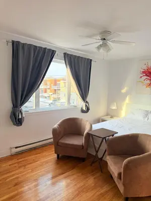 a bedroom with two chairs and a bed and a window at Cozy & spacious 3 BDR condo in Montréal
