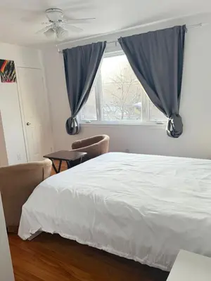 a bedroom with a bed with blue curtains and a window at Cozy & spacious 3 BDR condo in Montréal