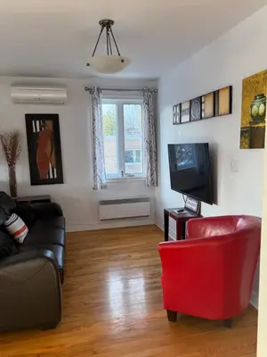 a living room with a black couch and a red chair at Cozy & spacious 3 BDR condo in Montréal