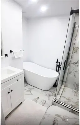 a white bathroom with a tub and a shower at Cute 2 BDR condo in Montréal
