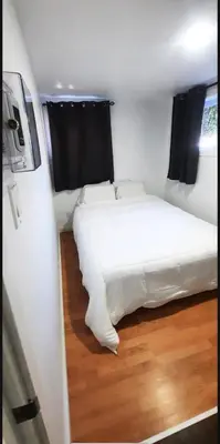 a bedroom with a white bed and a wooden floor at Cute 2 BDR condo in Montréal