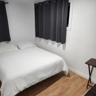 a bedroom with a bed with white sheets and a window at Cute 2 BDR condo in Montréal