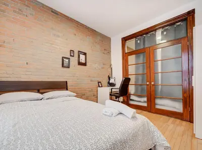 a bedroom with a large bed and a brick wall at Great 3B unit on Saint-Urbain in Montréal