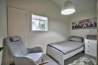 a bedroom with a bed and a chair and a window at Le Southière, minimum 30 nuits in Magog-Orford
