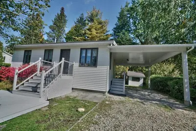 a small white house with a porch and stairs at Le Southière, minimum 30 nuits in Magog-Orford