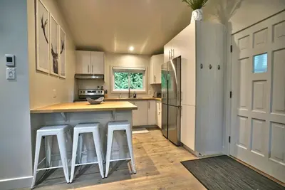 a kitchen with white cabinets and a island with bar stools at Le Southière, minimum 30 nuits in Magog-Orford