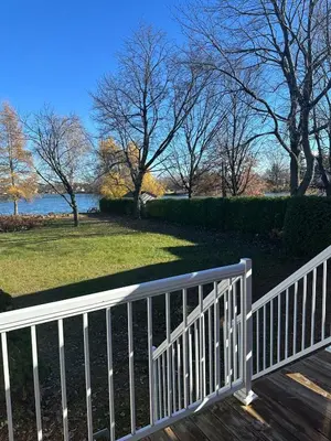 a white fence on a wooden deck with a view of a park at Pointe Calumet, 30 minutes de Montréal max 8 pers in Pointe-Calumet