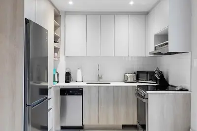 a kitchen with white cabinets and a stainless steel refrigerator at Boho Luxe 2-Floor Retreat Sleeps 6 Private Patio in Montréal
