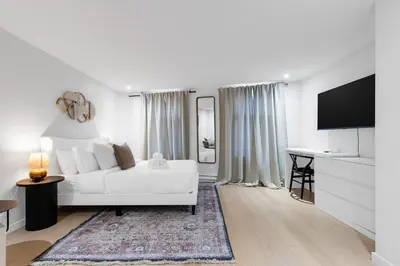 a white living room with a white couch and a television at Boho Luxe 2-Floor Retreat Sleeps 6 Private Patio in Montréal