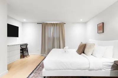 a white bedroom with a bed and a television at Boho Luxe 2-Floor Retreat Sleeps 6 Private Patio in Montréal