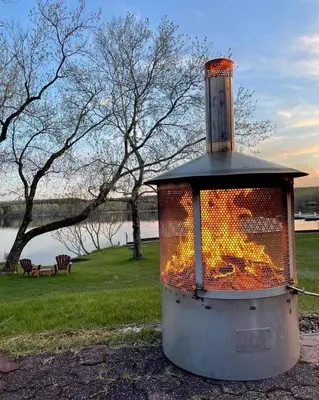 a stove with fire inside of it in a park at Auberge l'Intermède du lac in Disraeli