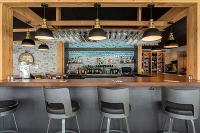 a bar with four stools in front of a counter at Auberge l'Intermède du lac in Disraeli