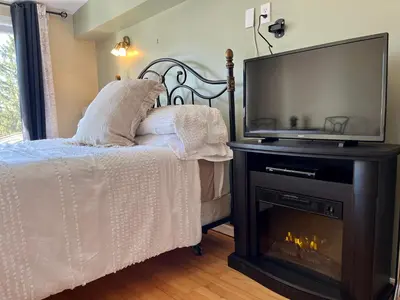 a bedroom with a bed with a fireplace and a television at Auberge l'Intermède du lac in Disraeli