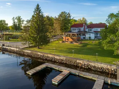 a large house with a river in front of it at Auberge l'Intermède du lac in Disraeli
