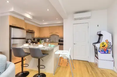 a kitchen with a refrigerator and a table and chairs at Take a break in a modern loft on the plateau Walk score 99 in Montréal