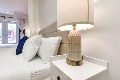 a lamp on a white table next to a bed at Take a break in a modern loft on the plateau Walk score 99 in Montréal