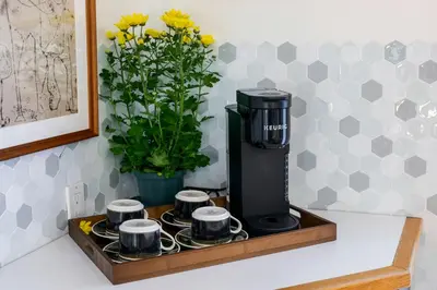 a coffee maker on a tray with cups and flowers at Cozy Montreal Entire Apartment-3min walk to Metro-free parking-Botanical garden-biodome in Montréal