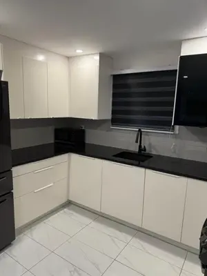a kitchen with white cabinets and a black refrigerator at Rima in Montréal
