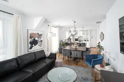 a living room with a black couch and a dining room at Mont Royal Prime Residence in Montréal