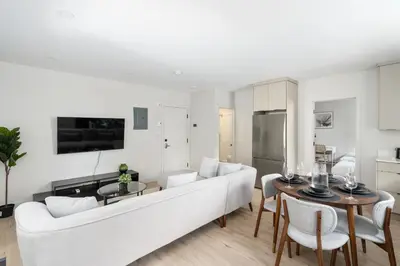 a white living room with a white couch and a table at The Griffin ApartHotel- Downtown in Montréal
