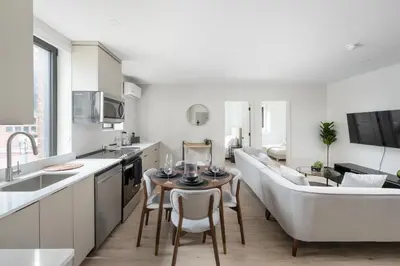 a kitchen and living room with a couch and a table at The Griffin ApartHotel- Downtown in Montréal