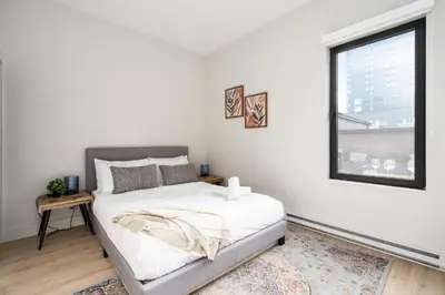 a white bedroom with a bed and a window at The Griffin ApartHotel- Downtown in Montréal