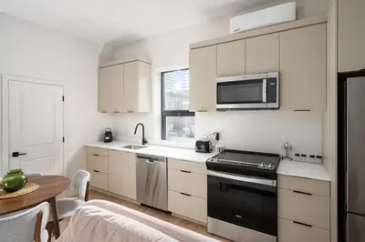 a kitchen with white cabinets and a black appliance at The Griffin ApartHotel- Downtown in Montréal