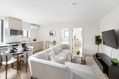 a white living room with a couch and a table at The Griffin ApartHotel- Downtown in Montréal