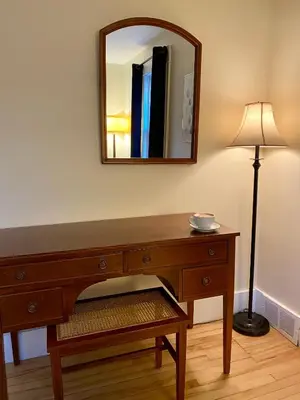 a dresser with a mirror and a lamp in a room at Auberge Le Sunshine in Stanstead Plain