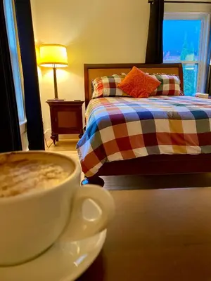a cup of coffee sitting on a table next to a bed at Auberge Le Sunshine in Stanstead Plain
