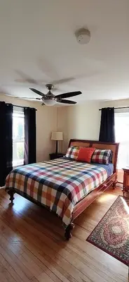 a bedroom with a bed and a ceiling fan at Auberge Le Sunshine in Stanstead Plain