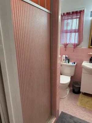 a pink bathroom with a toilet and a shower door at Downtown Montreal Airport 15Mins in Montréal