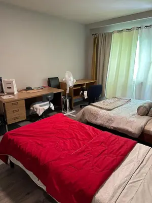 a bedroom with two beds and a desk and a red blanket at Downtown Montreal Airport 15Mins in Montréal