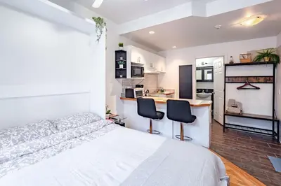 a bedroom with a bed and two chairs and a kitchen at Studio COZY - Rue Ste-Catherine in Montréal