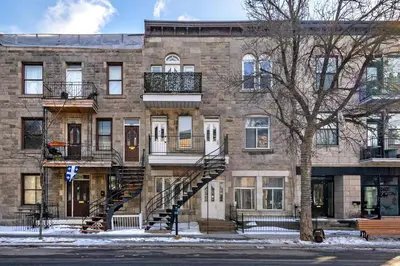 a large brick building with a staircase in front of it at Studio COZY - Rue Ste-Catherine in Montréal