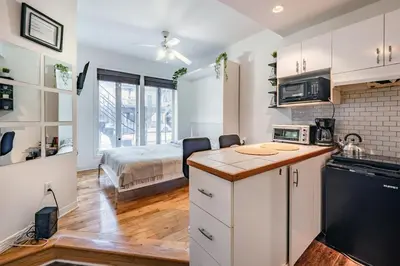 a kitchen with white cabinets and a bed in a room at Studio COZY - Rue Ste-Catherine in Montréal