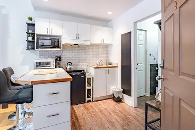 a kitchen with white cabinets and a counter top at Studio COZY - Rue Ste-Catherine in Montréal