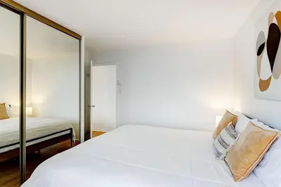 a white bedroom with a bed and a mirror at LaCité Apartments Modern Comfort Close to Downtown Montreal in Montréal