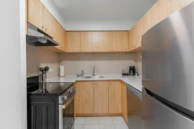 a kitchen with wooden cabinets and a stainless steel refrigerator at LaCité Apartments Modern Comfort Close to Downtown Montreal in Montréal