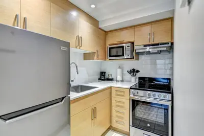 a kitchen with wooden cabinets and a stainless steel refrigerator at LaCité Apartments Modern Comfort Close to Downtown Montreal in Montréal