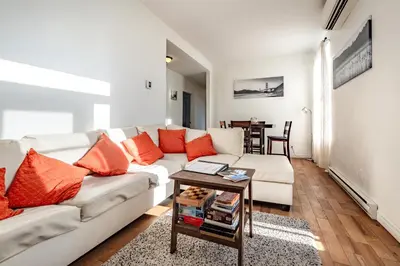 a living room with a white couch and orange pillows at Apartment ROOMY - Plateau Mont-Royal in Montréal
