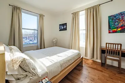 a bedroom with a bed and a desk and windows at Apartment ROOMY - Plateau Mont-Royal in Montréal