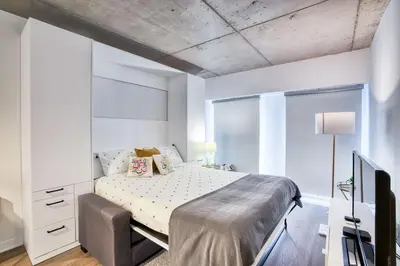 a white bedroom with a bed and a tv at Welcome Chez Milou in Montréal