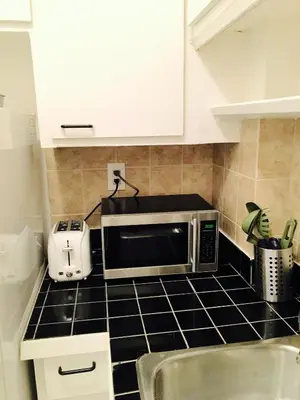 a kitchen with a microwave on a black counter top at Stylish Montreal Apartment Comfortable Stay in the Golden Square Mile in Montréal