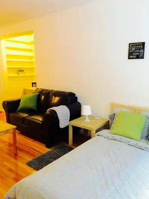 a living room with a leather couch and a bed at Stylish Montreal Apartment Comfortable Stay in the Golden Square Mile in Montréal