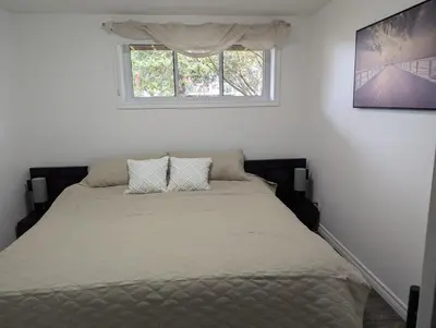 a bed in a white room with a window at Lac et Montagne Eastman in Eastman