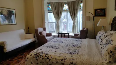 a bedroom with a bed and a couch and windows at Gingerbread Manor in Montréal