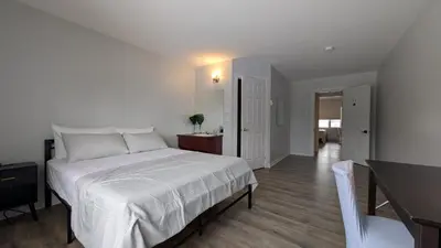 a bedroom with a large white bed and a hallway at Hotel Room in Varennes in Varennes