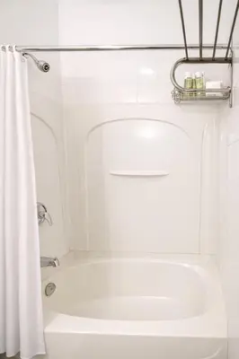 a white bath tub with a shower curtain in a bathroom at Hotel Room in Varennes in Varennes