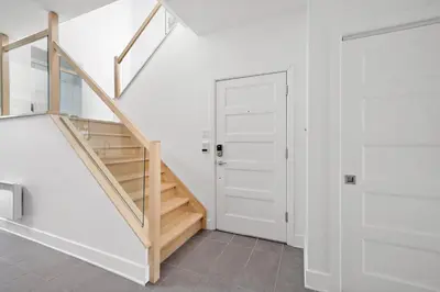 a white hallway with a staircase and a door at 3 bedroom Penthouse Great for family vacation in Montréal